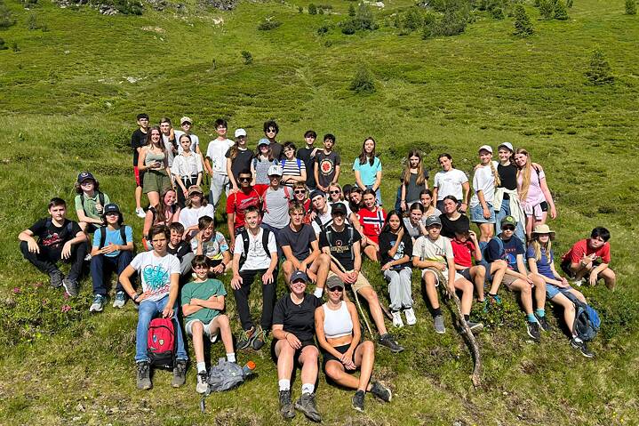 Eine große Gruppe posiert auf einer Wiese für ein Erinnerungsfoto.
