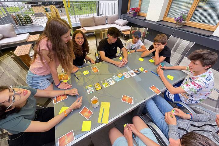 Jugendliche spielen Karten an einem Tisch im Freien.