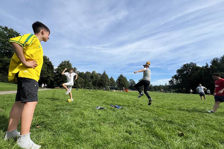 Jugendliche spielen Ball auf einer grünen Wiese.