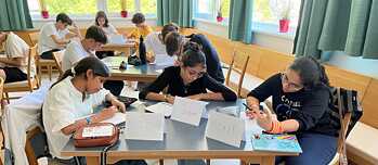 Jugendliche sitzen an Tischen in einem Klassenzimmer und arbeiten konzentriert.