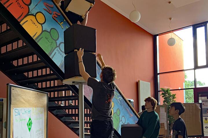Jugendliche stapeln große Kartons neben einer Treppe.