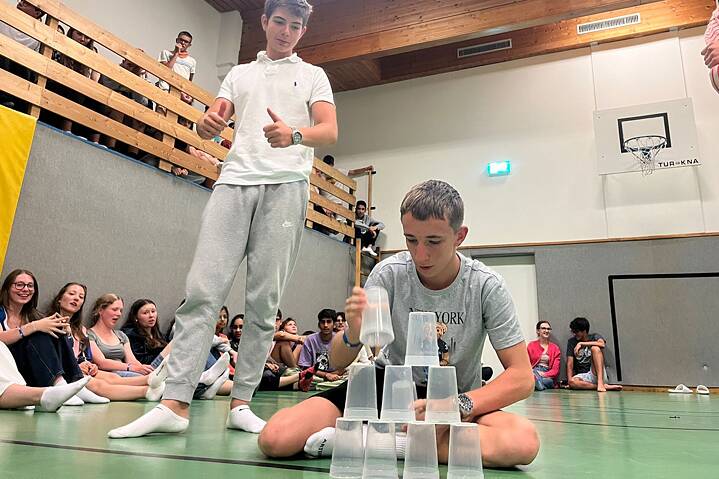 Ein Jugendlicher baut einen Turm aus leeren Gläsern.