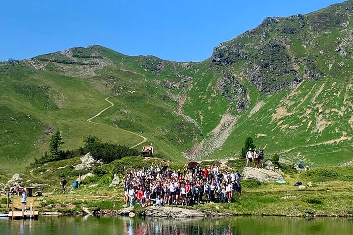 Ein Gruppe Jugendlicher an einem Seeufer in den Alpen