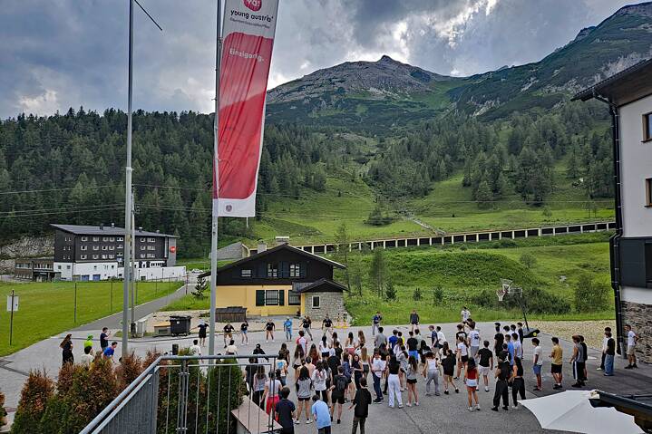 Jugendliche tanzen auf einem Hof, im Hintergrund sieht man die Berge.