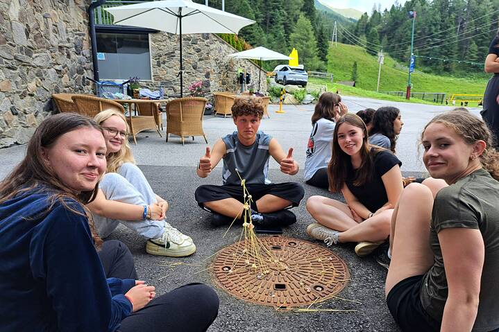 Jugendliche sitzen auf dem Fußboden und spielen Mikado.