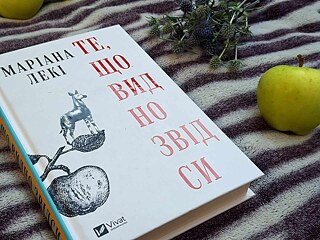 Книжка лежить поряд із яблуком та іграшкою