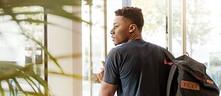 A young man walks outside of a building. 