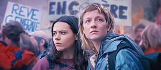 Das Bild zeigt zwei junge Frauen, die nebeneinander auf einer Demonstration stehen.