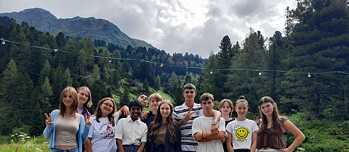 Jugendliche posieren für ein Gruppenbild vor alpenländischer Kulisse.