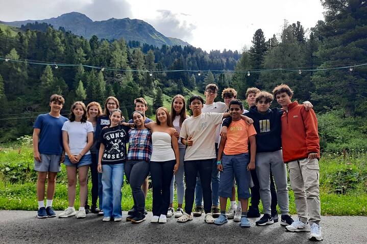 Jugendliche posieren für ein Gruppenbild vor alpenländischer Kulisse.