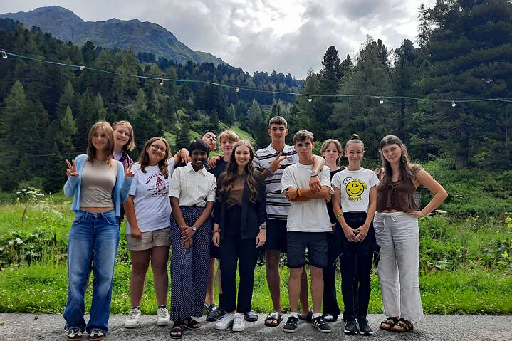 Jugendliche posieren für ein Gruppenbild vor alpenländischer Kulisse.
