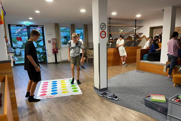 Jugendliche in einem Raum spielen und sind mit Smartphones beschäftigt.