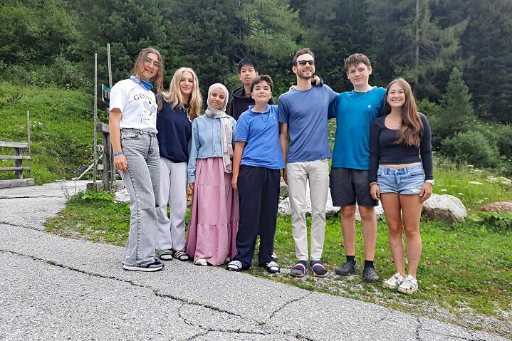 Eine kleine Gruppe posiert vor einer Bergkulisse.
