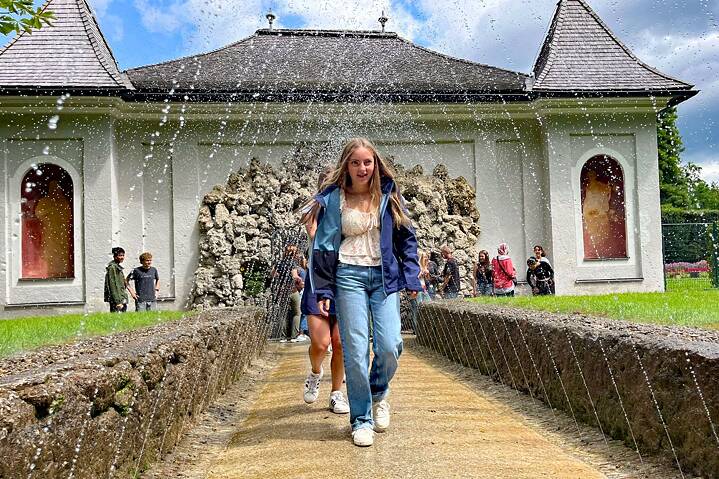 Jugendliche laufen unter den Wasserspielen.