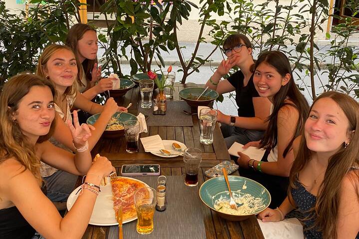 Jugendliche sitzen an einem Tisch und genießen sichtlich italienisches Essen.