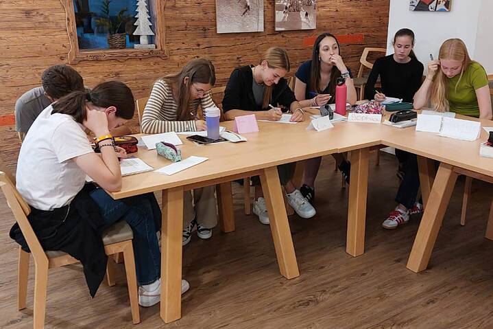 Jugendliche arbeiten konzentriert an einem langen Tisch.