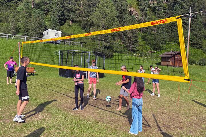 Jugendliche spielen Volleyball auf einer Wiese.