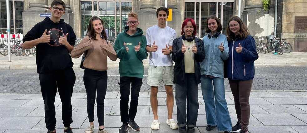 Die Jugendlichen stehen auf dem Platz vor dem alten Gebäude