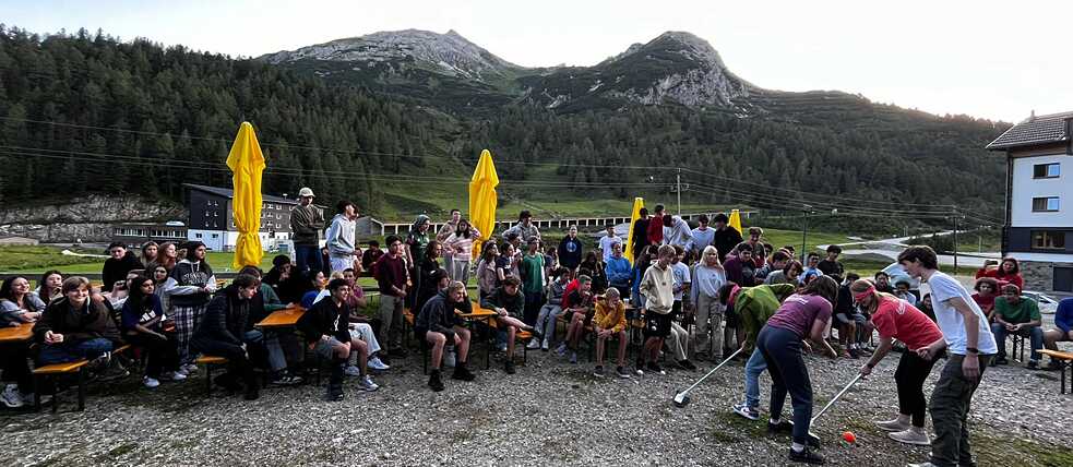 Eine große Gruppe Jugendlicher amüsiert sich auf einer Wiese.