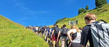 Jugendliche mit Rucksäcken auf einem Pfad in den Alpen