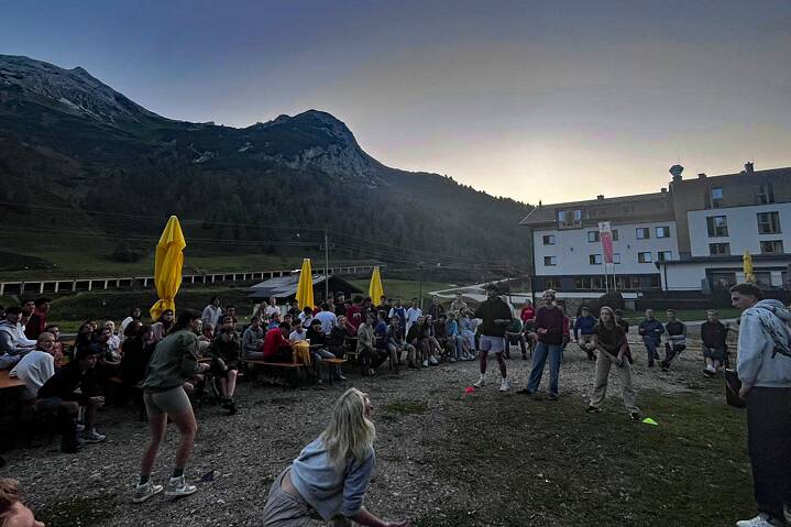 Eine große Gruppe Jugendlicher amüsiert sich auf einer Wiese.