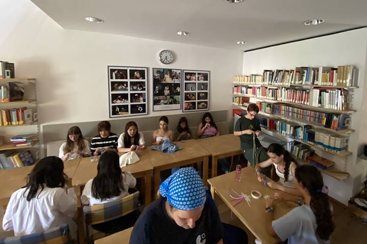 Jugendliche in einem Raum knüpfen Armbänder.