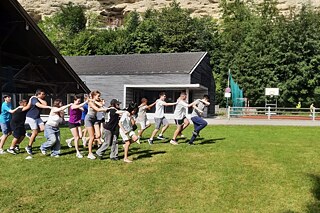 Jugendliche spielen auf einer Wiese vor Schloß Stein.