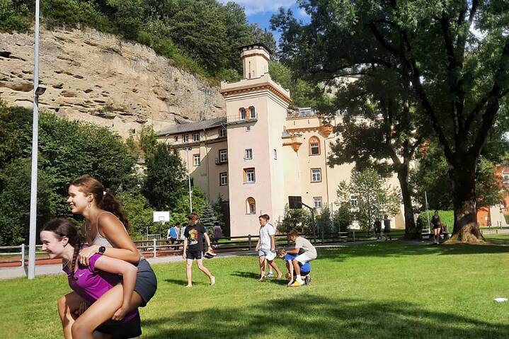 Jugendliche und junge Erwachsene spielen auf einer Wiese vor Schloß Stein.