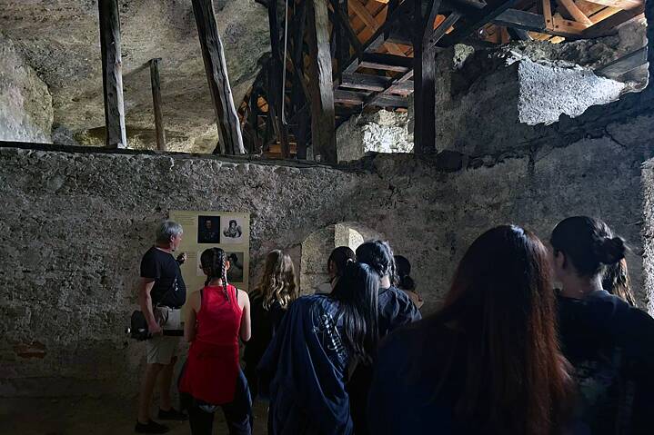 Jugendliche in einem alten Steinbau vor einer Erläuterungstafel