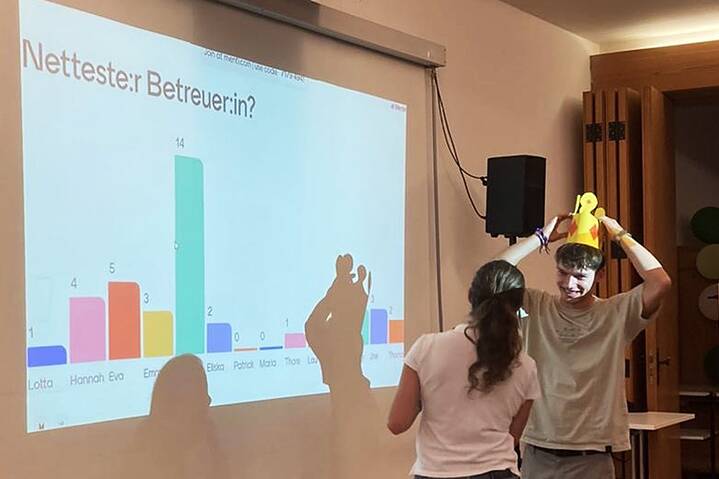 Ein junger Erwachsener setzt sich eine gelbe Krone aus Papier auf den Kopf.