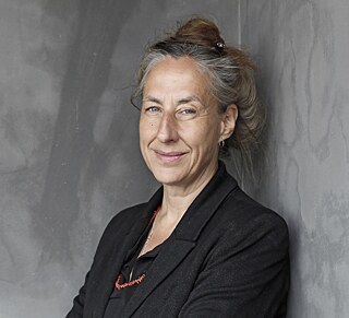 Judith Hermann: Frau mittleren Alters vor grauem Hintergrund