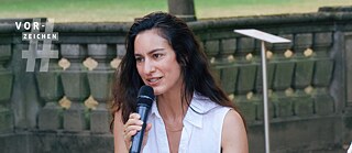 Auf dem Bild ist die Literaturkritikerin Maryam Aras zu sehen, die auf einer Diskussionsveranstaltung in ein Mikro spricht.