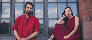 A man and a woman sitting outside in front of window
