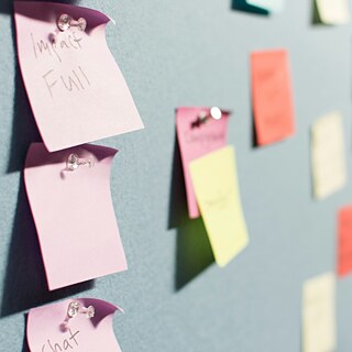 Bunte Notizzettel sind an einer Pinnwand befestigt. Einige Zettel sind beschriftet, andere leer.