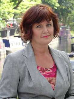 Porträt von Annette, einer Dame mit roten Haaren, die eine graue Anzugjacke trägt.