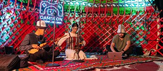 Menschen spielen in einer Jurte Instrumente und fördern so eine gemeinschaftliche und festliche Atmosphäre.