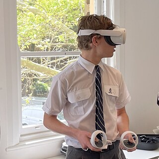 Junge in einem Klassenzimmer, der eine Virtual-Reality-Brille trägt und völlig in seine digitale Erfahrung eintaucht.