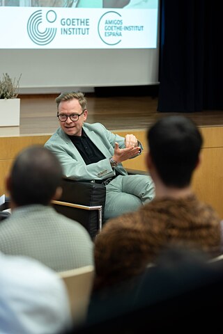 Una vista desde el público a la mesa de debate con Markus Gabriel en el centro
