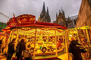 Festively illuminated children's carousel at the Christmas market in front of Cologne Cathedral