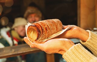 Woman at the Christmas market hands Baumstriezel over the counter