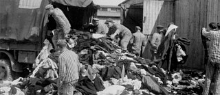 Image en noir et blanc de personnes en tenue de prisonnier du camp de concentration sur un camion chargé de vêtements