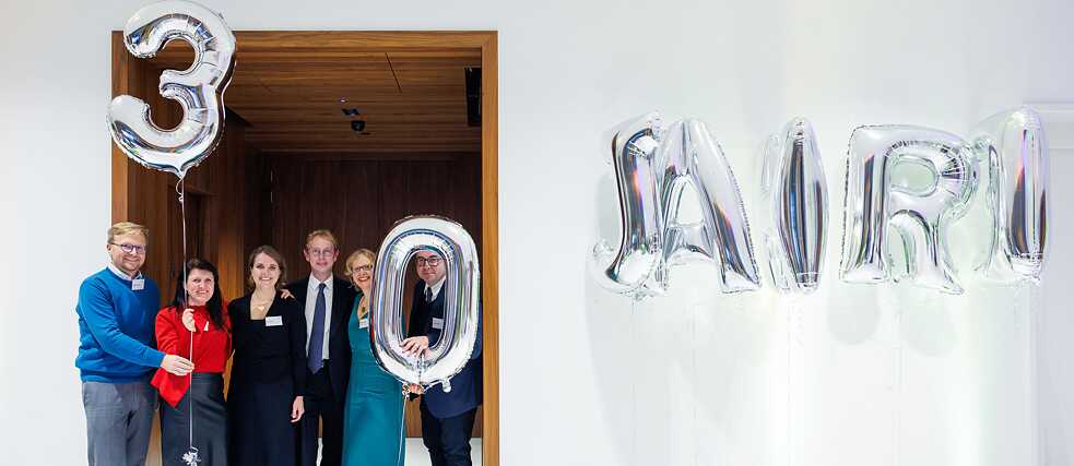 Teilnehmer*innen der Jubiläumsveranstaltung posieren mit silbernen Luftballons mit dem Schriftzug 30 Jahre 