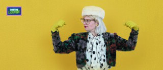 A singer with strong arms in front of a yellow background