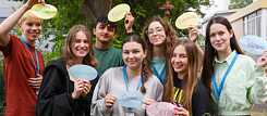 PASCH-Schüler*innen lächeln in die Kamera und halten bunte Zettel mit deutschen Wörtern nach oben.