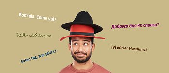 Mann mit zwei Hüten auf dem Kopf und mehreren Sprachen im Hintergrund