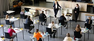 Schüler*innen sitzen an getrennten Tischen