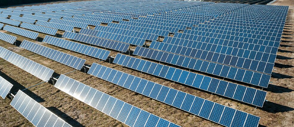 A large solar farm with multiple rows of solar panels installed on a grassy field, capturing sunlight for renewable energy generation.