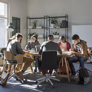 A team of learners seated at a table in an office, actively involved in a face-to-face language learning session.