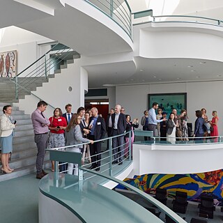 Participants of the network meeting stand in a group on one floor in the Federal Chancellery in Berlin.