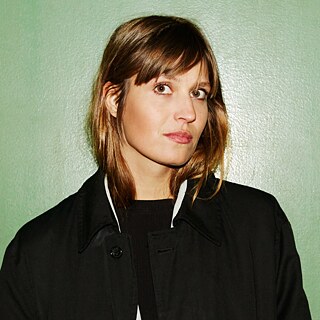 Forfatteren Charlotte Gneuss står foran en grøn baggrund.